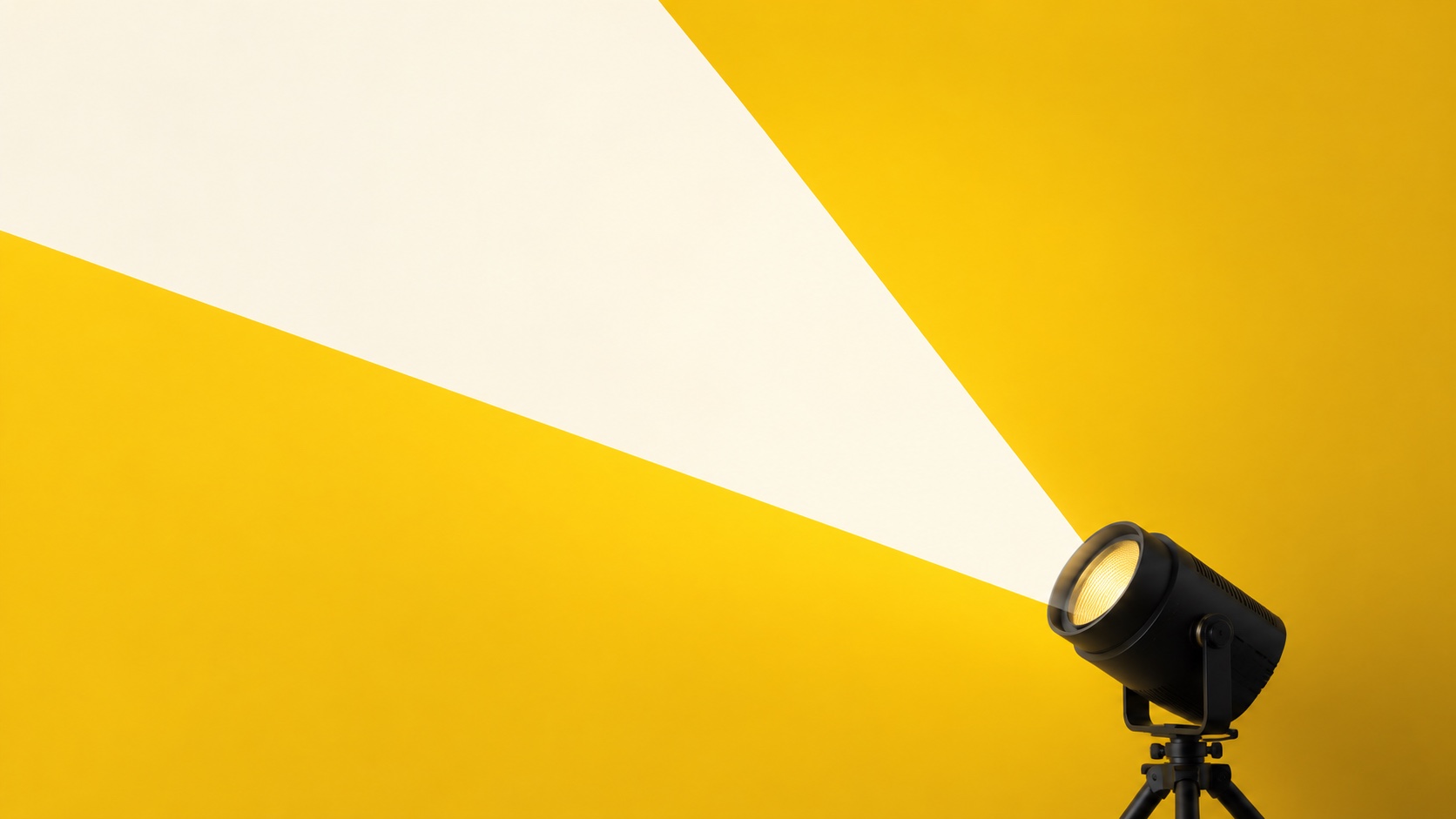 A black spotlight casting a pale beam across a golden-yellow wall.